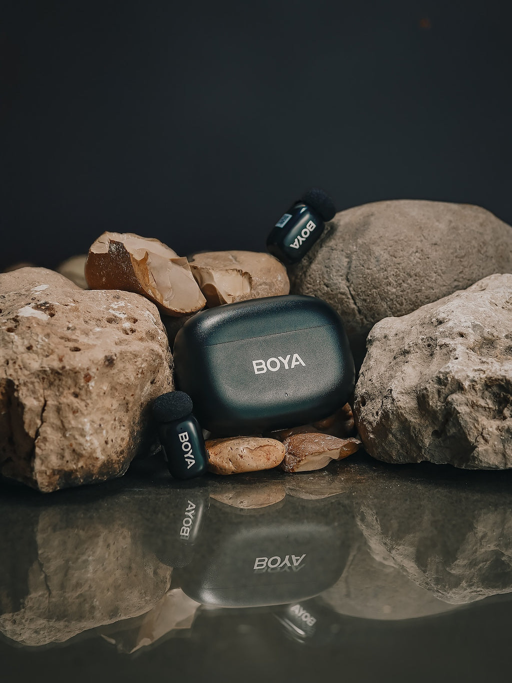 BOYA microphone and receiver on rocks with a dark background