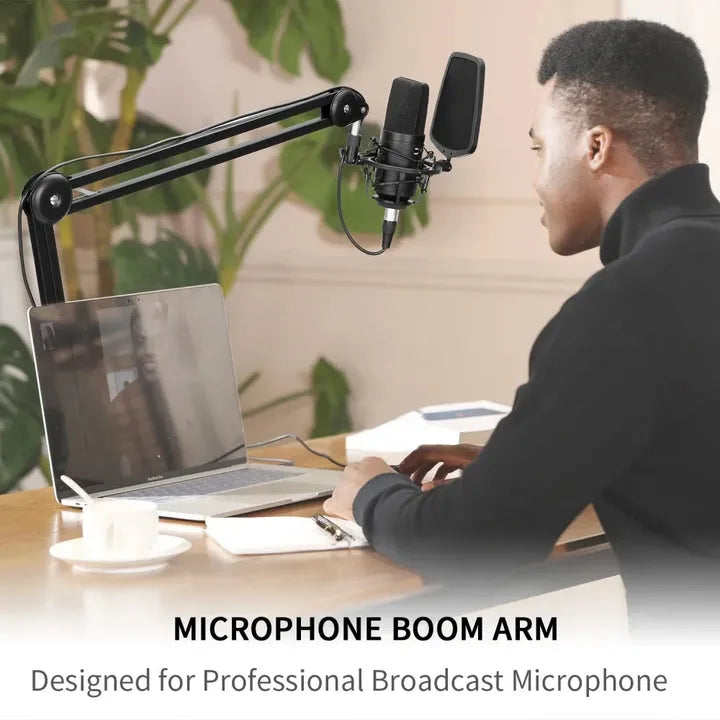 Person using a professional broadcast microphone with a microphone boom arm in a home office setting.